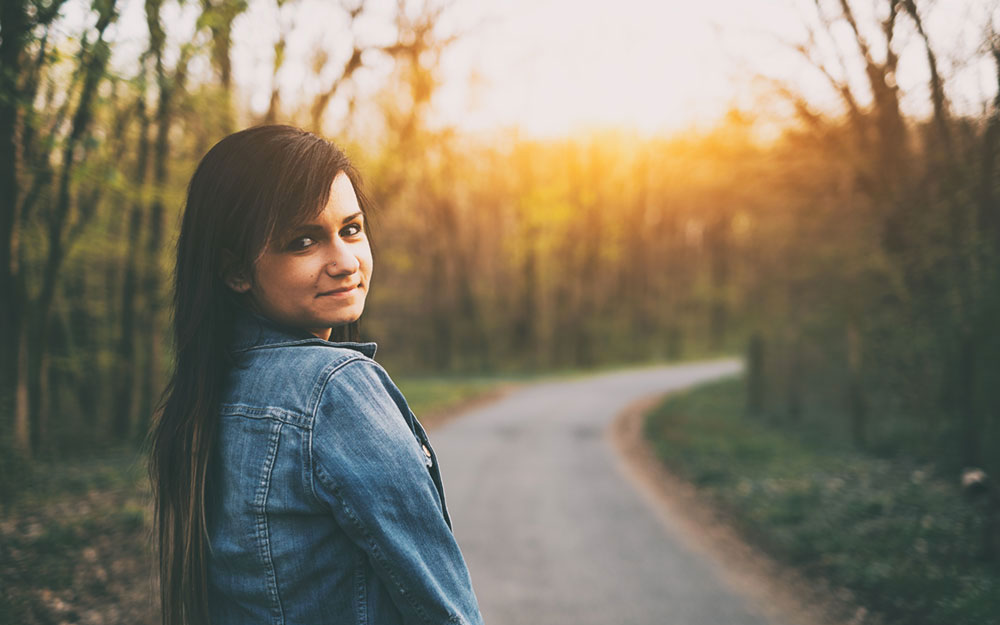 woman looking over her shoulder outside on a path