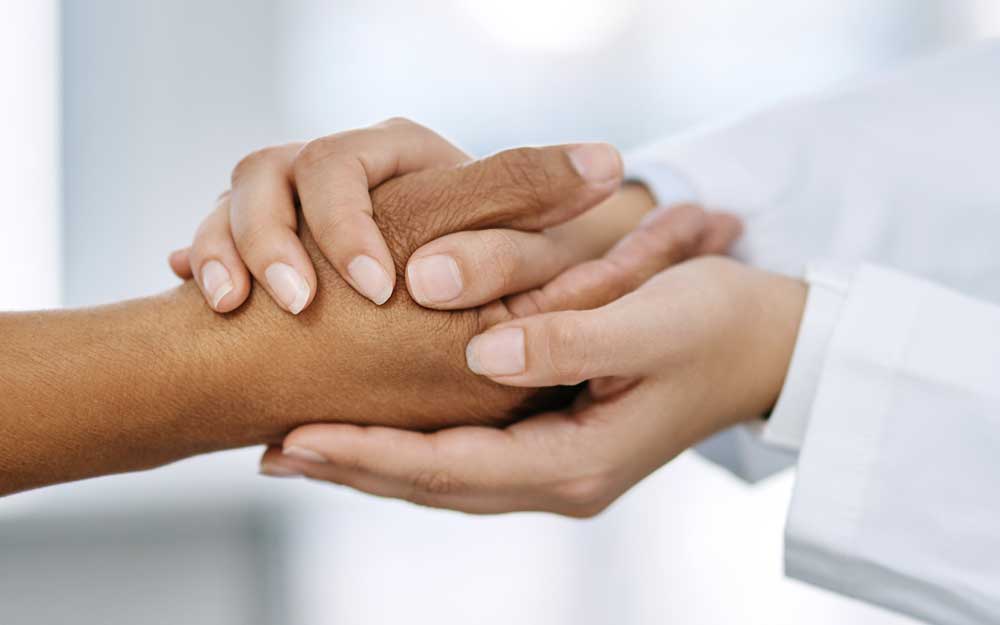 Trusted provider in lab coat holds the hand of a patient