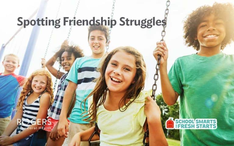 The image features a group of six smiling children standing close together in a playground. They are varied in appearance and are visibly joyful, suggesting they are enjoying the activity or company. The background includes swing sets and a sunny sky, typical of a vibrant outdoor playground scene. The children wear casual summer clothing in bright colors, adding to the lively atmosphere.Transcribed Text: Spotting Friendship Struggles