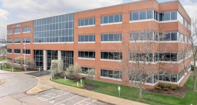 A large red brick office building with glass windows and white column entrance.
