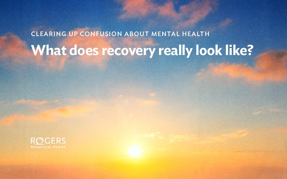 The image depicts a vibrant sky during sunrise or sunset, featuring rich orange, pink, and blue hues. Transcribed Text: CLEARING UP CONFUSION ABOUT MENTAL HEALTH What does recovery really look like?