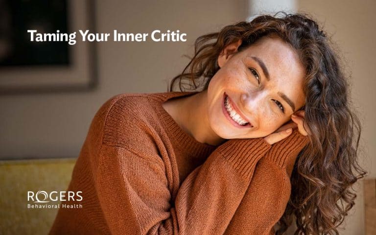 This image features a woman smiling because she has overcome negative self-talk. White text in the corner reads: "Taming Your Inner Critic."