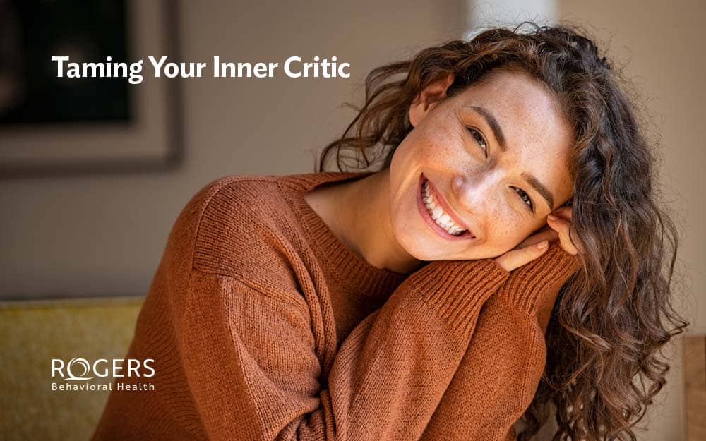 This image features a woman smiling because she has overcome negative self-talk. White text in the corner reads: "Taming Your Inner Critic."