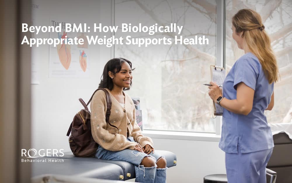 A young woman sits on an examination table, engaging with a healthcare professional about weight and eating disorders.