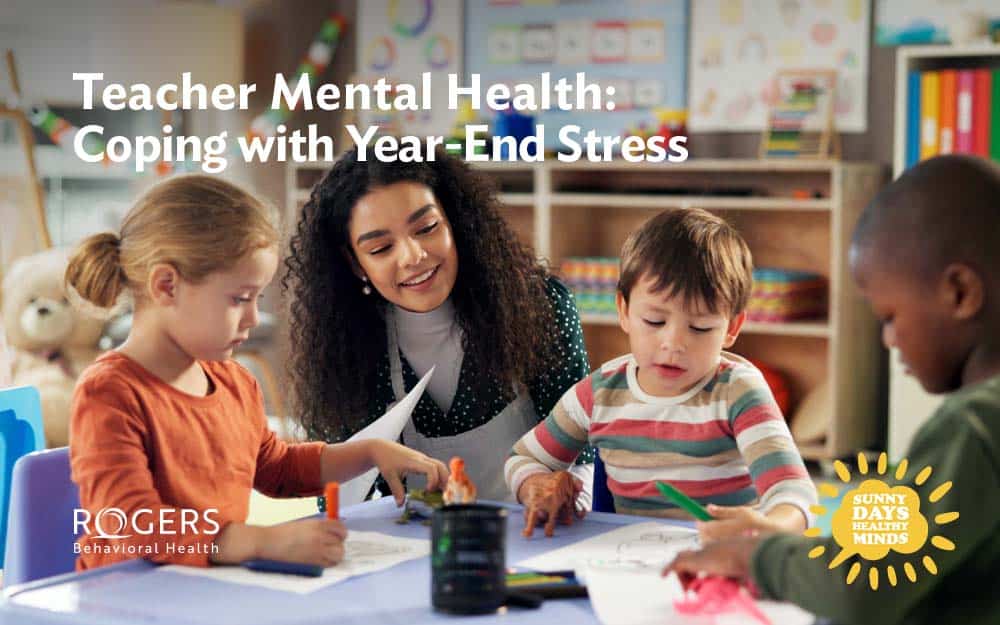 The image shows a teacher sitting at a table with three young children engaging in a coloring activity as she wraps up the end of the year balancing burnout. Transcribed Text: Teacher Mental Health: Coping with Year-End Stress. Graphic of a sun says Sunny Days, Healthy Minds