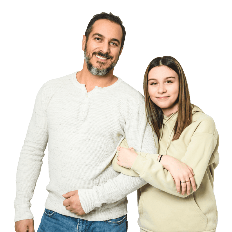 A smiling father and teen daughter standing closely together, both wearing light-colored clothing.