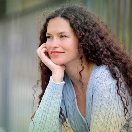 Woman resting her chin in her hand, gazing into the distance