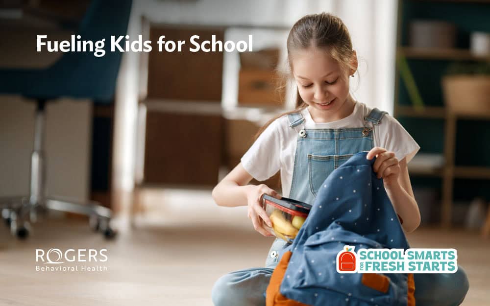 Image shows a child pulling out her lunch at school filled with healthy foods to fuel her physically and mentally. White text says: Fueling Kids for School