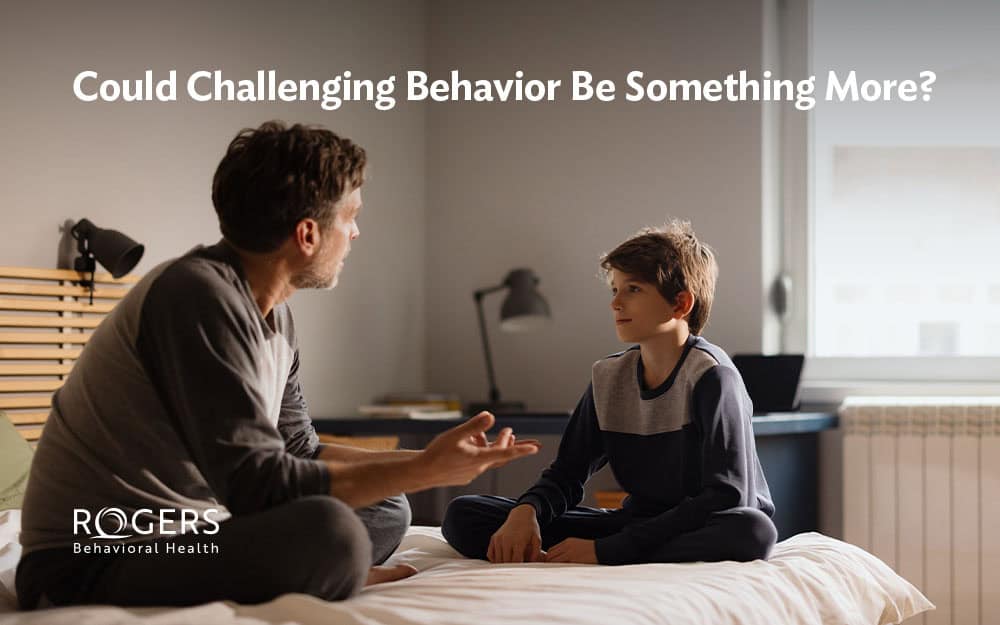 Image shows a father talking to his son about his behavior. Text says: Could Challenging Behavior Be Something More?