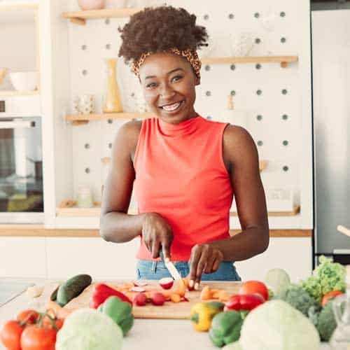 Woman chopping vegetables in a kitchen.